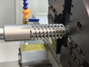 Close-up of a CNC machine tool executing high-precision thread milling on a large-diameter screw component with smooth surface finish.