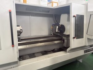 Internal view of the PH80 series Rotor Whirling Machine, showcasing the heavy-duty chuck, extended rigid machine bed, and spacious enclosed machining area.