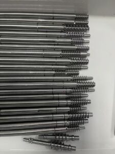 A display of several complex metal parts machined with high precision by the MX500 whirling machine. These parts feature a high surface finish and intricate details, highlighting the machine's advanced manufacturing capabilities, arranged against a clean, industrial background.