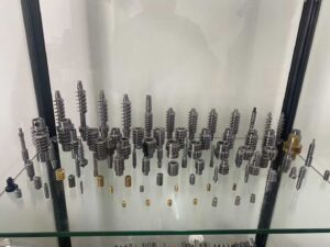 A display of several complex metal parts machined with high precision by the MX500 whirling machine. These parts feature a high surface finish and intricate details, highlighting the machine's advanced manufacturing capabilities, arranged against a clean, industrial background.