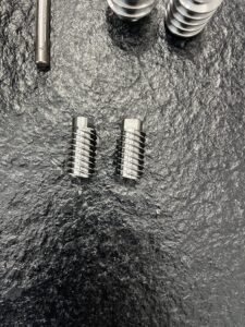 A display of several complex metal parts machined with high precision by the MX500 whirling machine. These parts feature a high surface finish and intricate details, highlighting the machine's advanced manufacturing capabilities, arranged against a clean, industrial background.