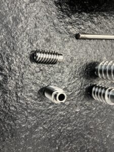 A display of several complex metal parts machined with high precision by the MX500 whirling machine. These parts feature a high surface finish and intricate details, highlighting the machine's advanced manufacturing capabilities, arranged against a clean, industrial background.