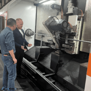 Close-up of a high-speed whirling milling cutter head with carbide inserts machining a precision thread on a metal shaft.
