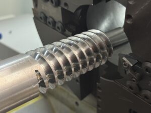 Close-up of a CNC machine tool executing high-precision thread milling on a large-diameter screw component with smooth surface finish.