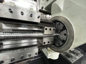 Close-up of a high-speed whirling milling cutter head with carbide inserts machining a precision thread on a metal shaft.